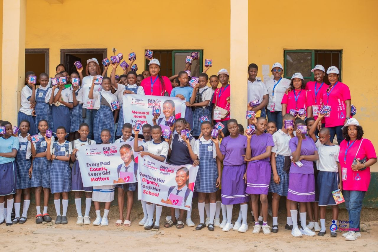 Students of Community Girls Secondary School, Elelenwo raising sanitary pads beside 'Every Pad Counts, Every Girl Matters' banners