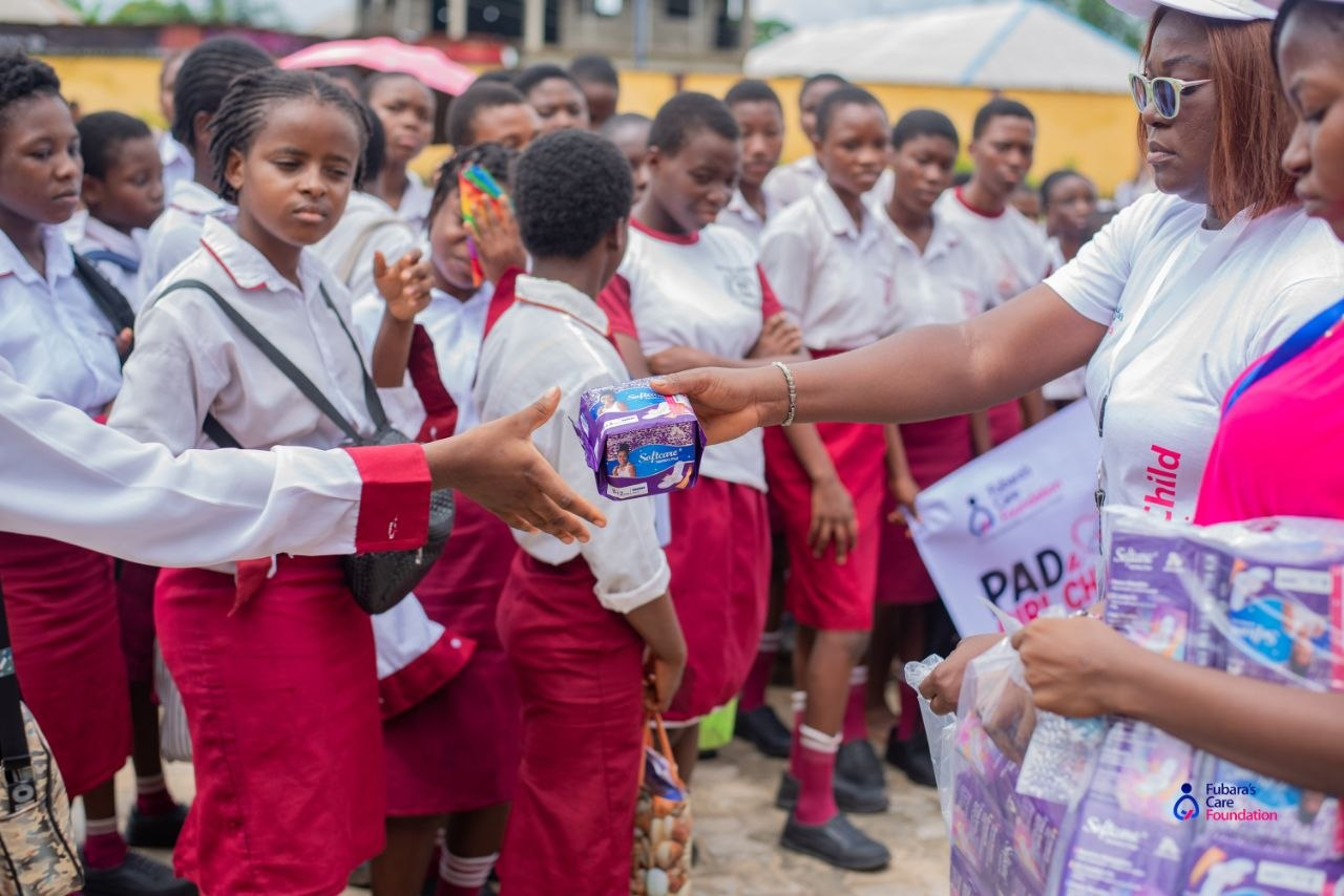 A volunteer handing a pack of sanitary pads to a student at Community Senior Secondary School, Akpajo