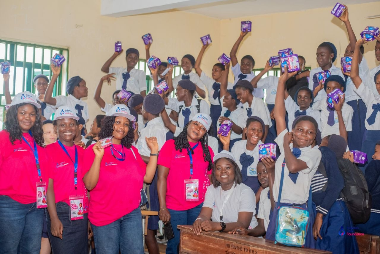 Students of Oba-Ama High School, Bakana raising sanitary pads received during the Pad a Girl Child Initiative