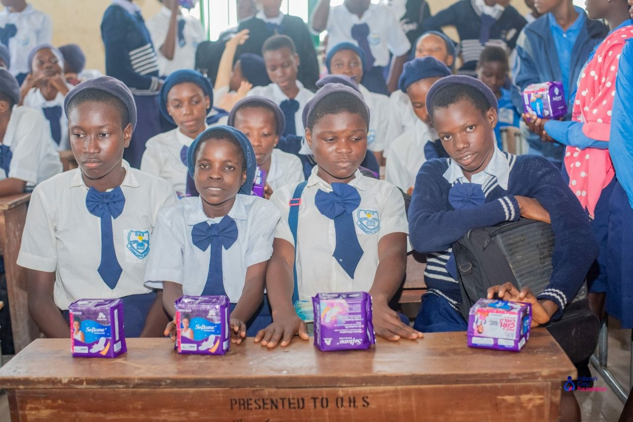 Students of Oba-Ama High School seated with their sanitary pad packs on a desk marked 'Presented to O.H.S'