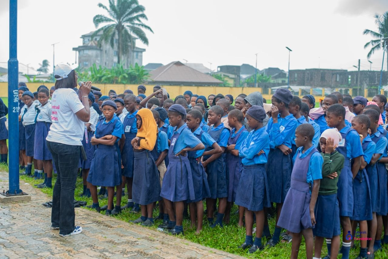 Open-air menstrual health assembly with hundreds of Oba-Ama High School students in Bakana